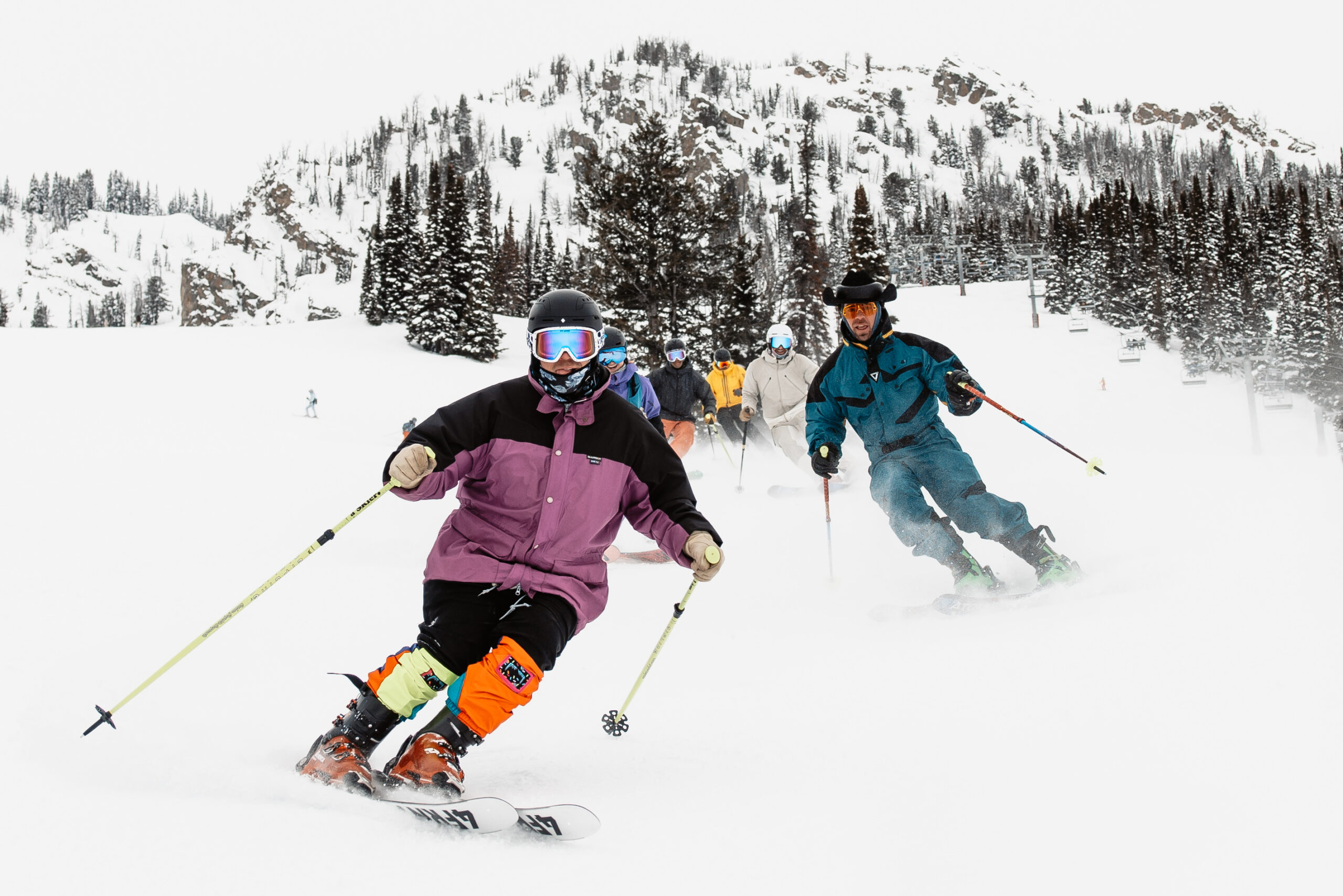 Skiers skiing in a line down a snowy slope