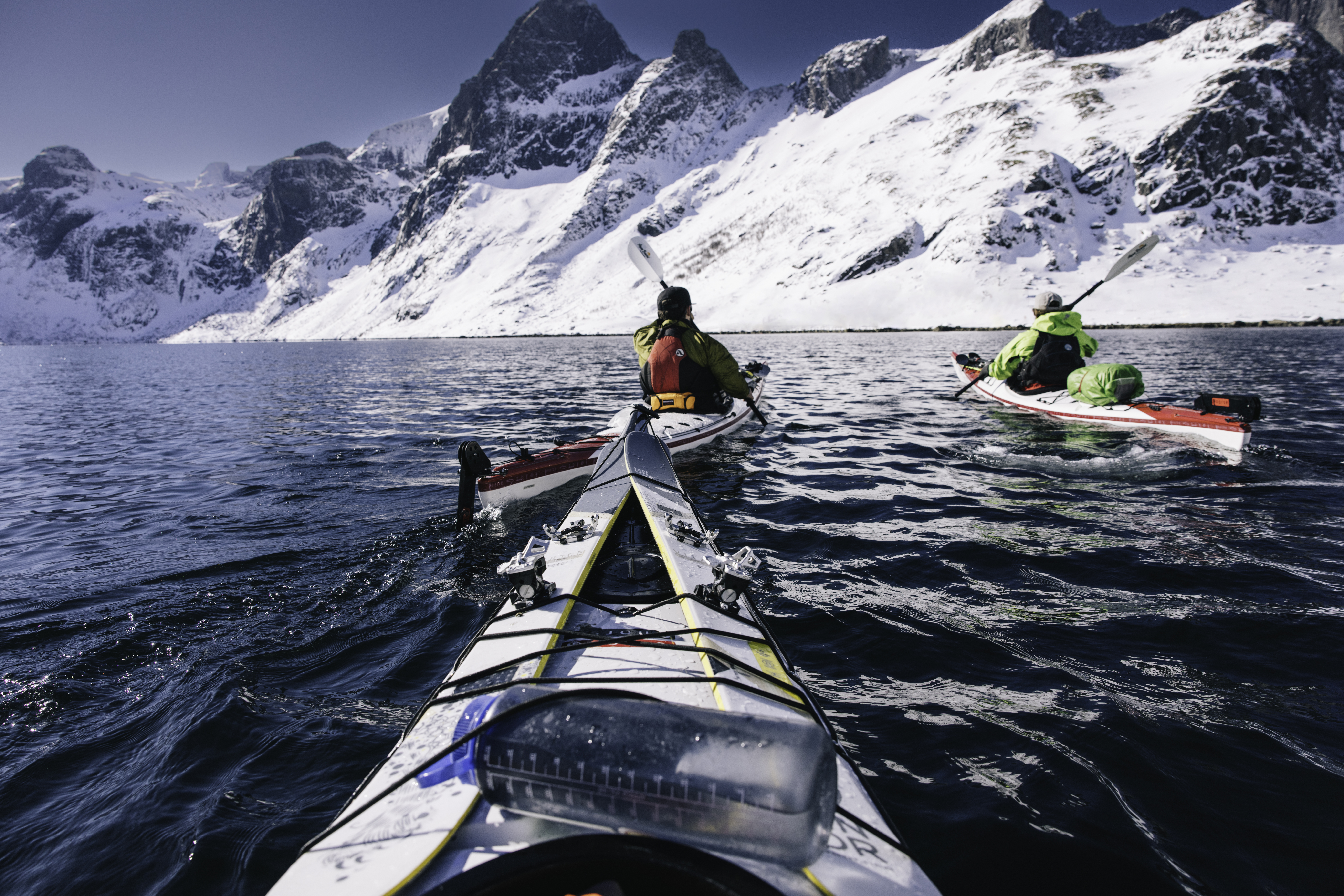 View of 2 kayakers in the ocean surrounded by mountains from a kayak