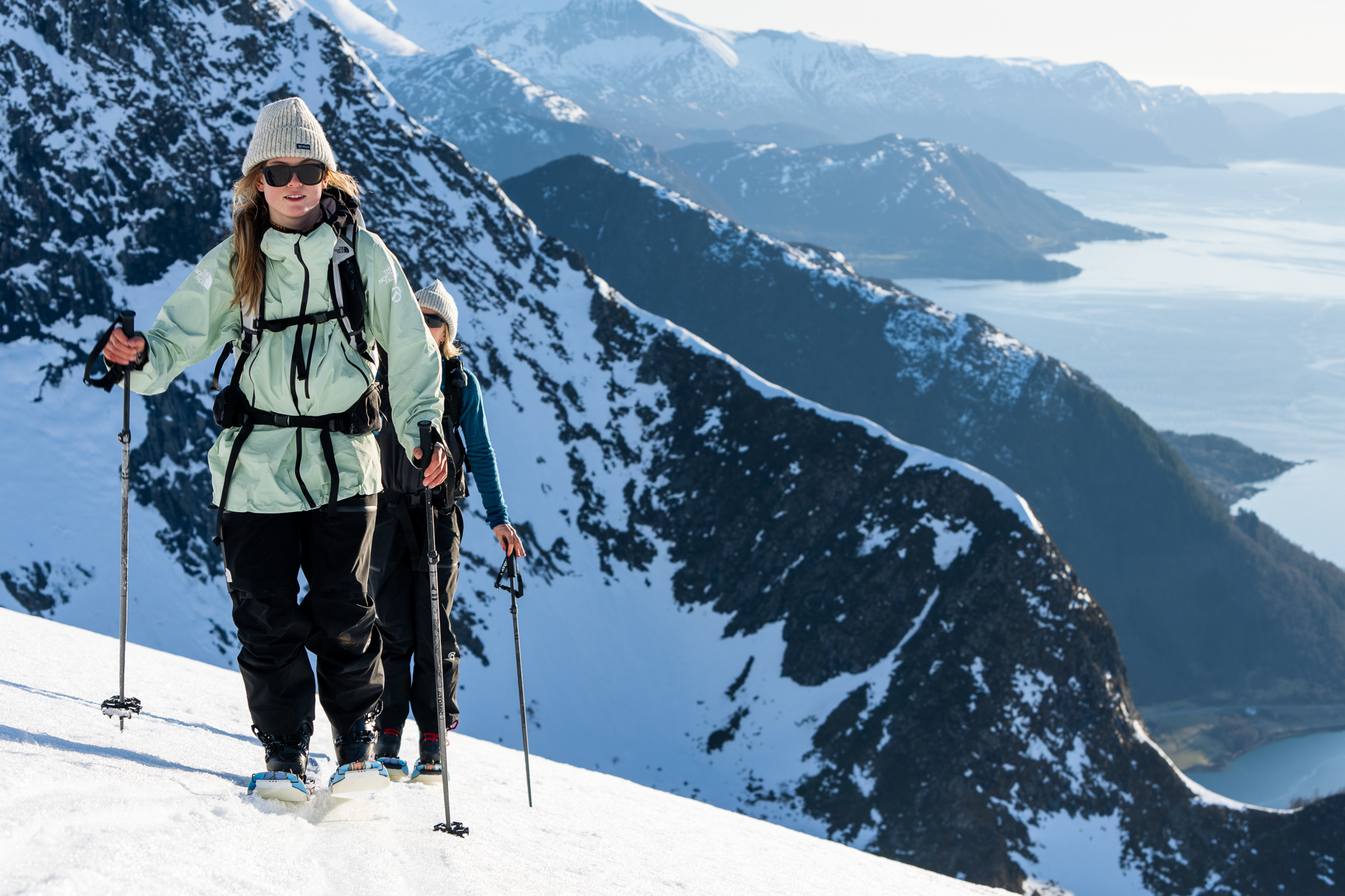 3 women skin on skis up the side of a steep mountain